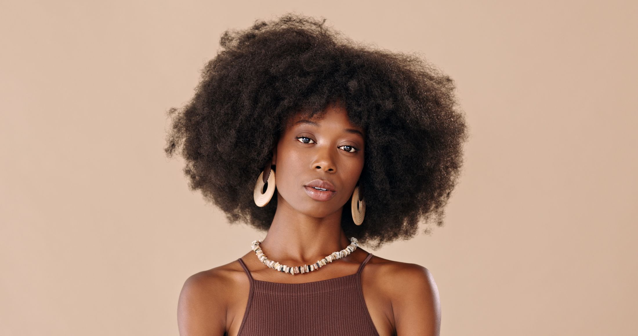 Woman with voluminous natural hair and jewelry.